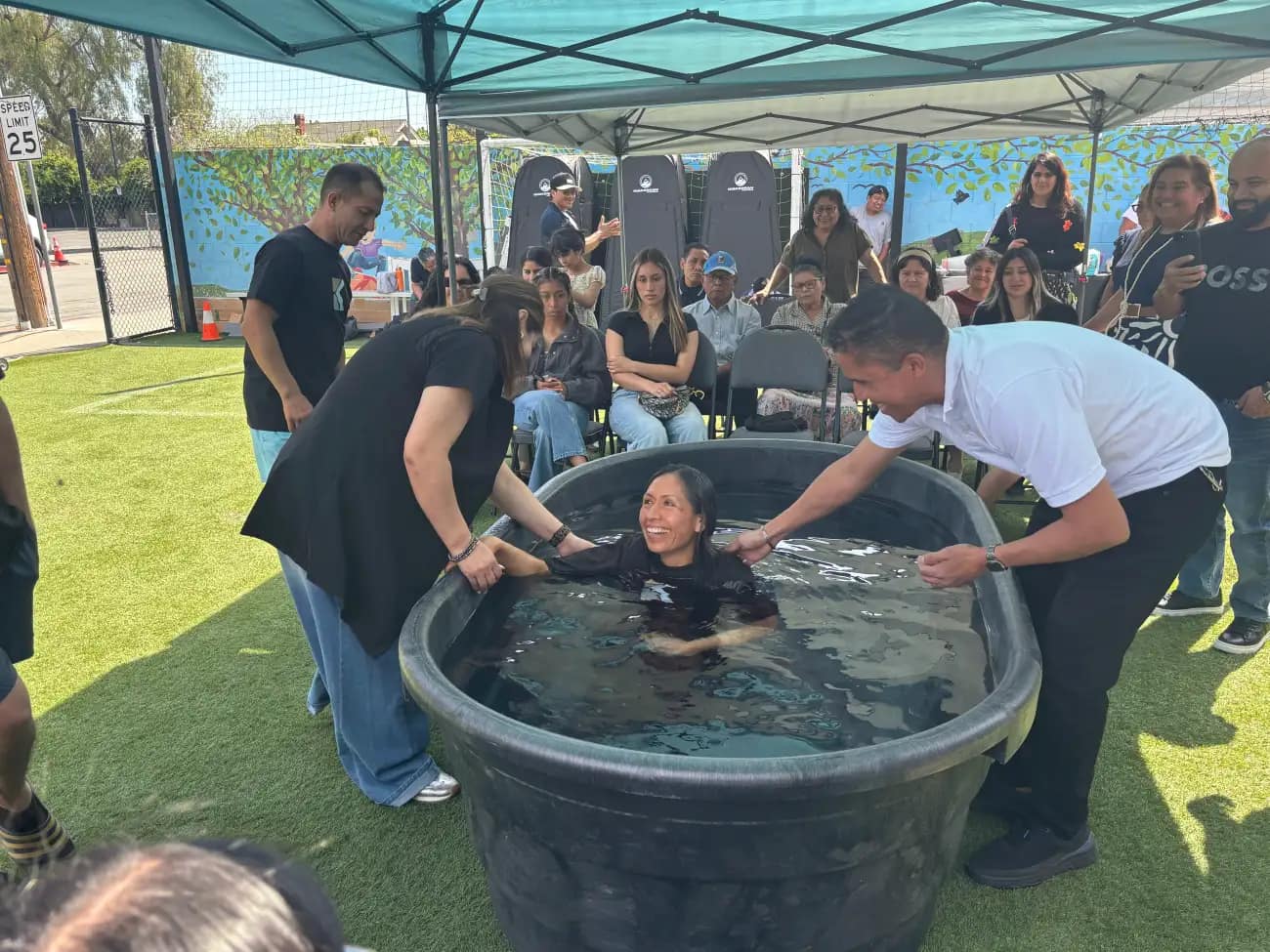 Una mujer es bajada al agua entre dos personas que la sujetan por los brazos