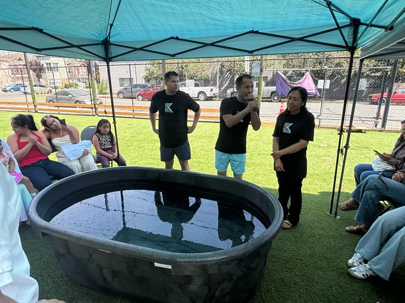 La pila llena de agua sobre el césped, con el equipo de la iglesia explicando lo que va a pasar
