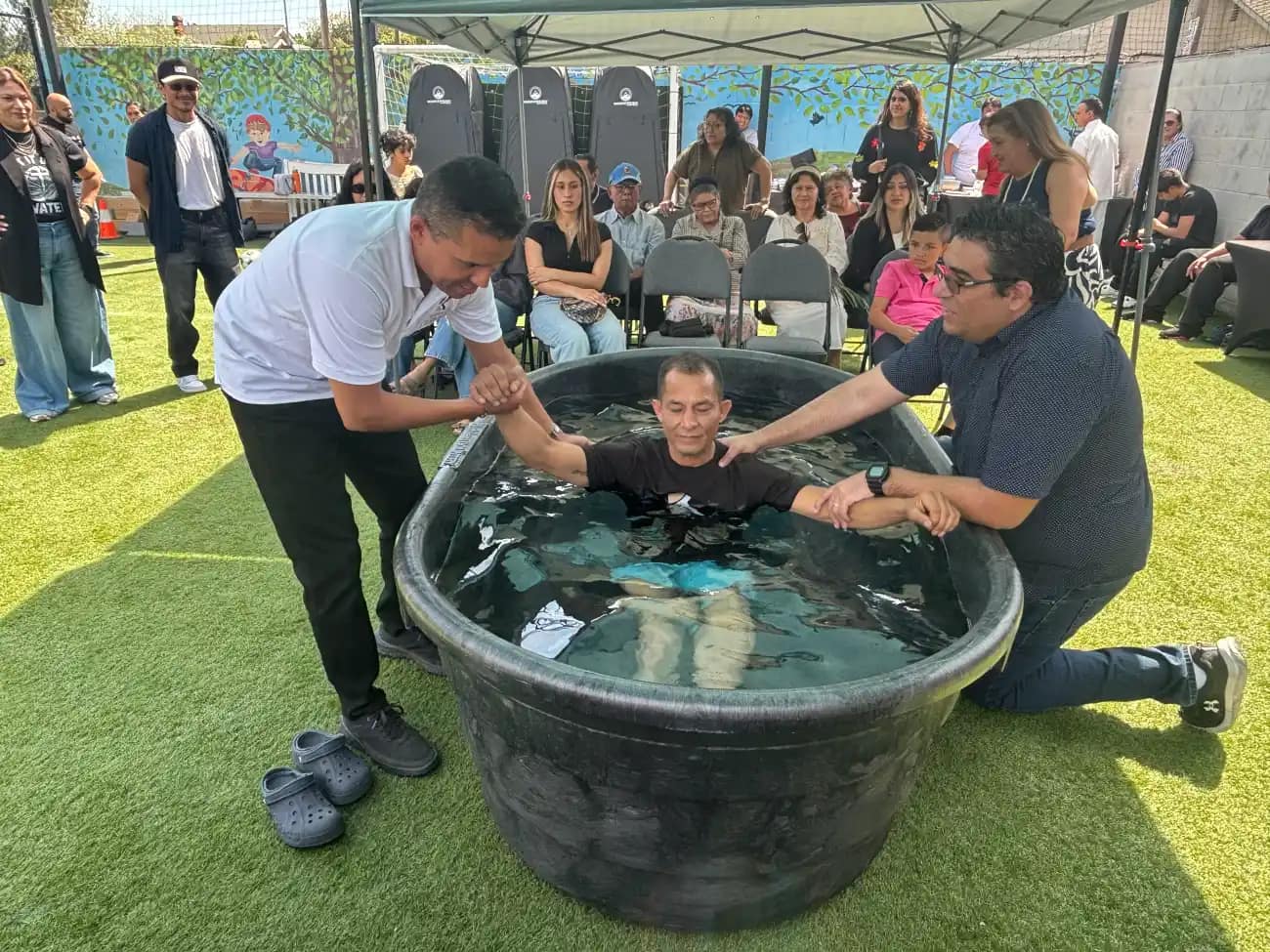 Los pastores sostienen a un hombre dentro de la pila en el momento de sumergirlo