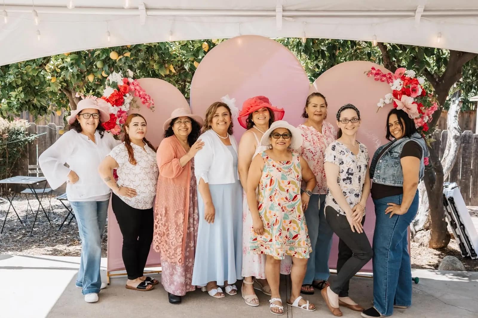 Grupo de mujeres posando delante del arco decorado con flores rosas y rojas