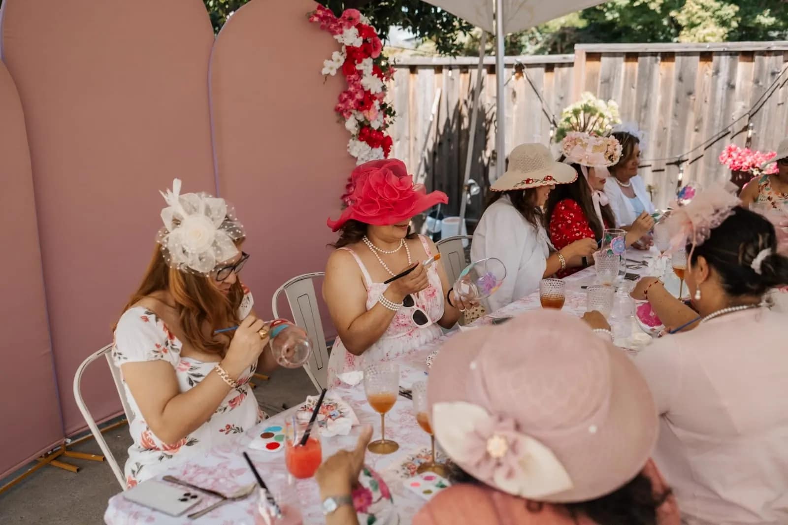 Dos mujeres con sombrero pintan copas de cristal durante el taller de la tarde