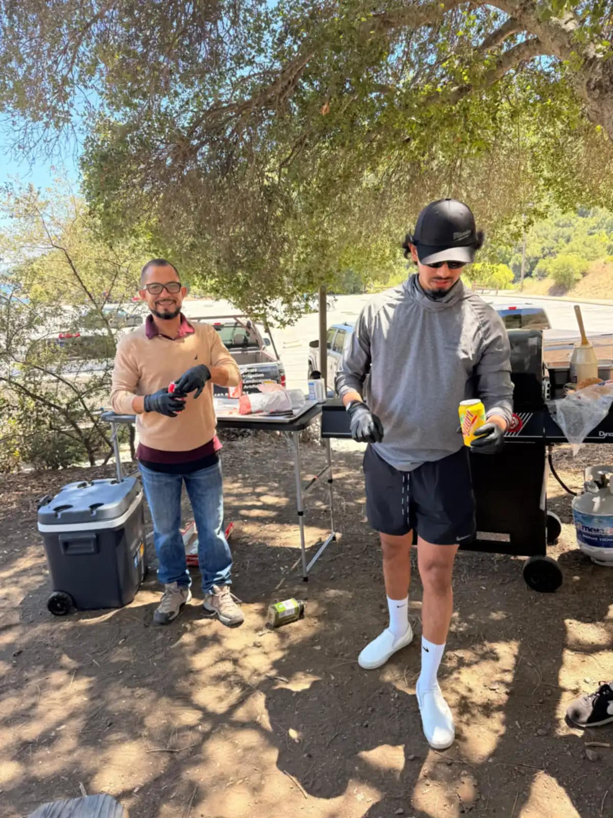 Cuatro hombres conversan alrededor de la parrilla mientras se hace la comida