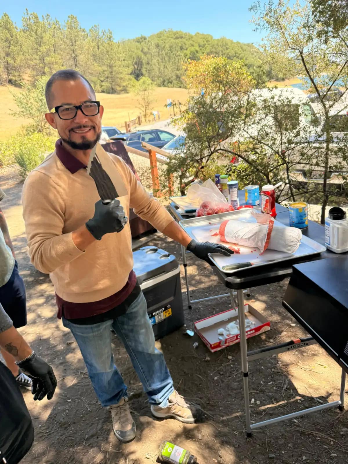 El cocinero levanta el pulgar con los guantes puestos delante de la mesa de preparación