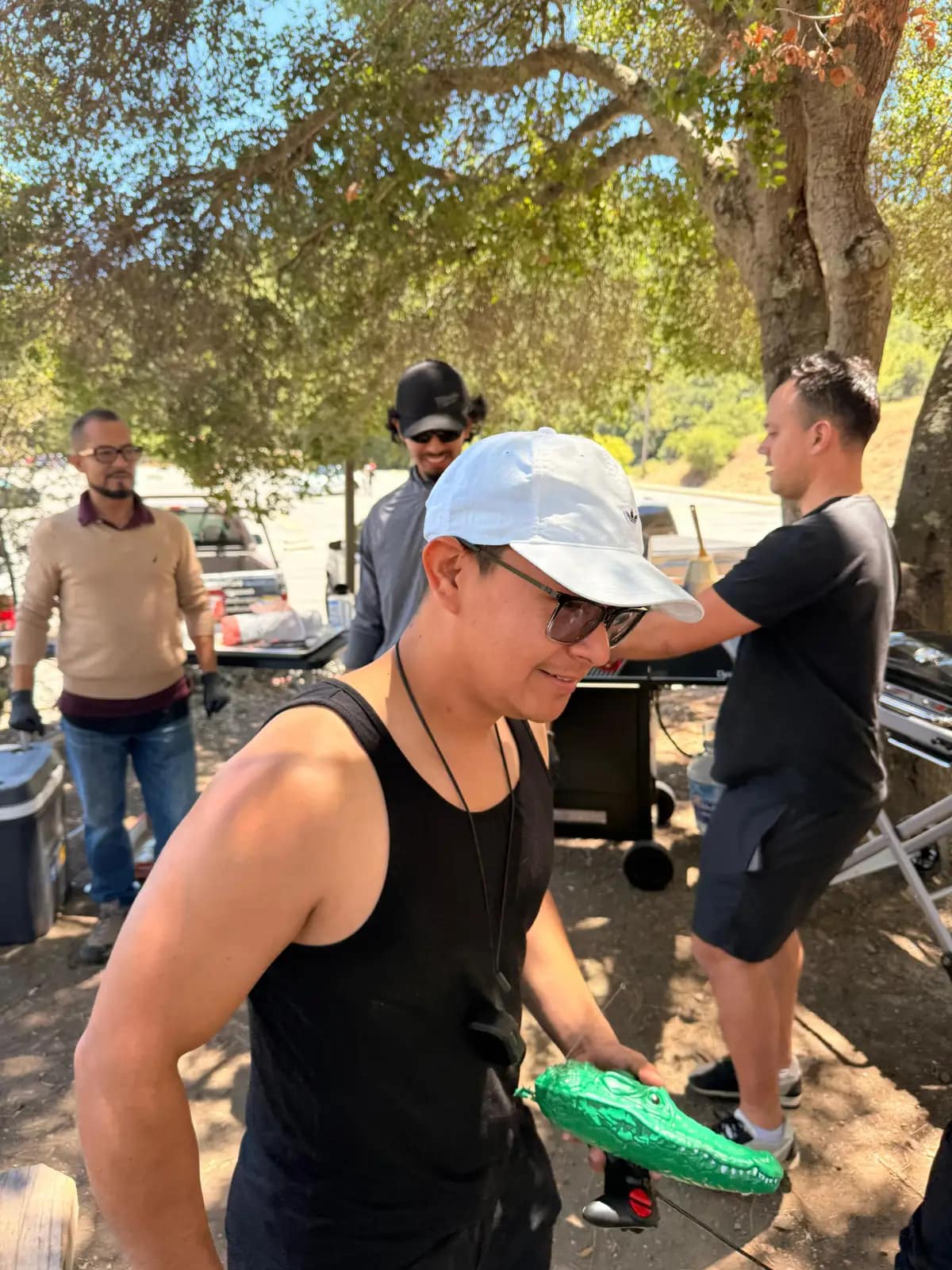 Un joven de gorra blanca pasea el cocodrilo de juguete entre los que preparan la parrilla