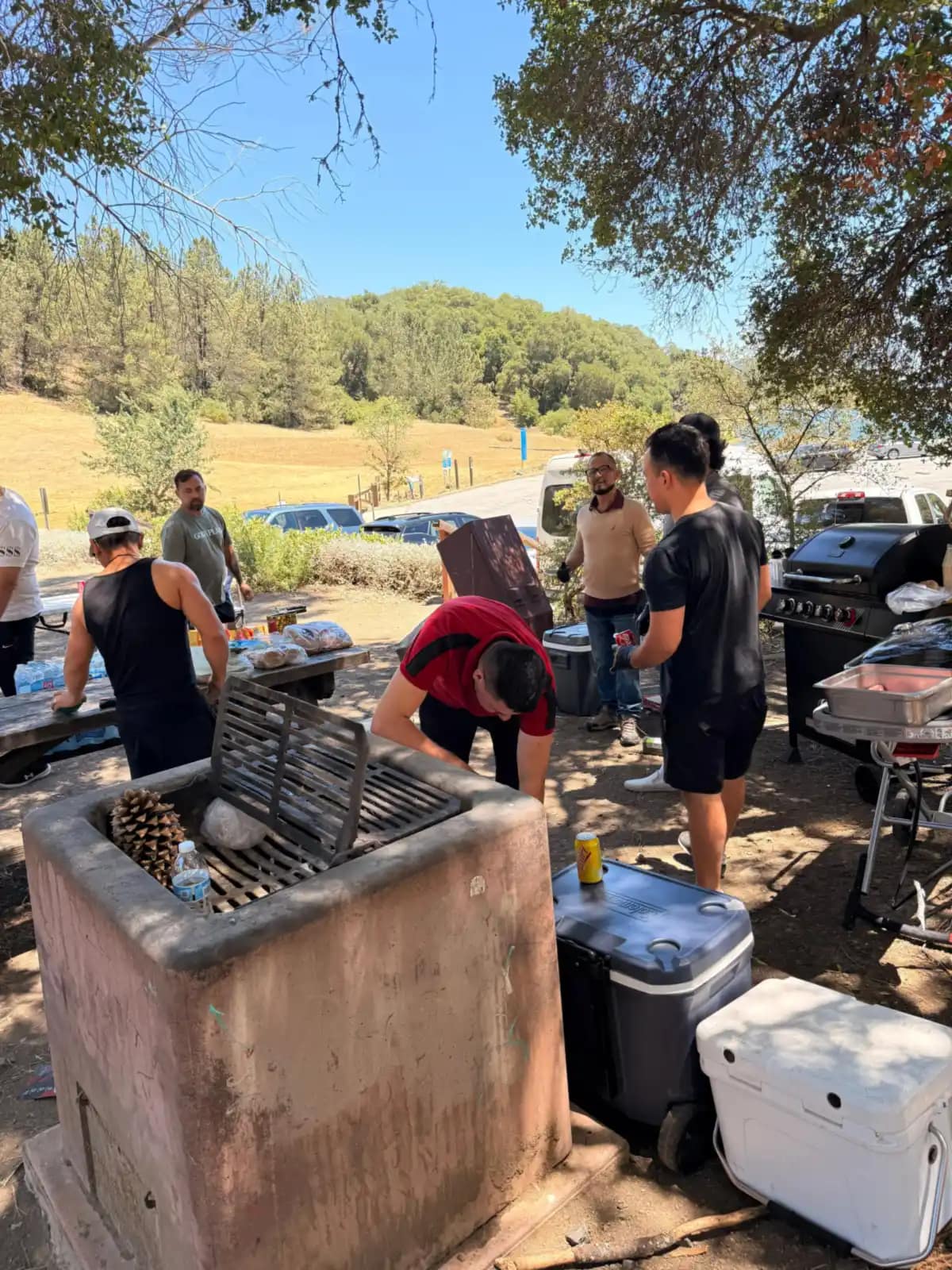 El grupo trabaja entre la barbacoa de piedra, las neveras y la parrilla de gas
