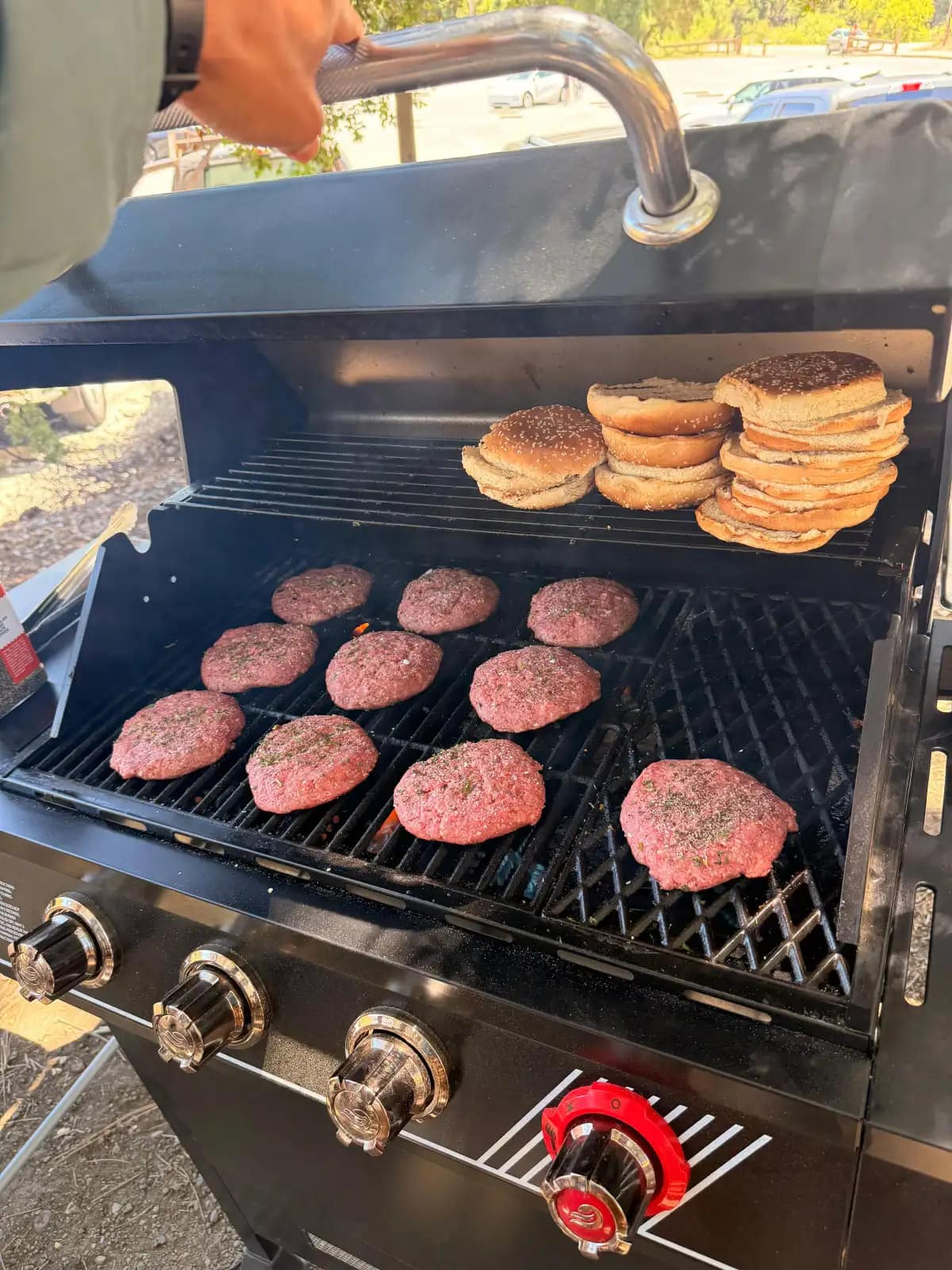 Las hamburguesas y los panes haciéndose sobre la parrilla de gas