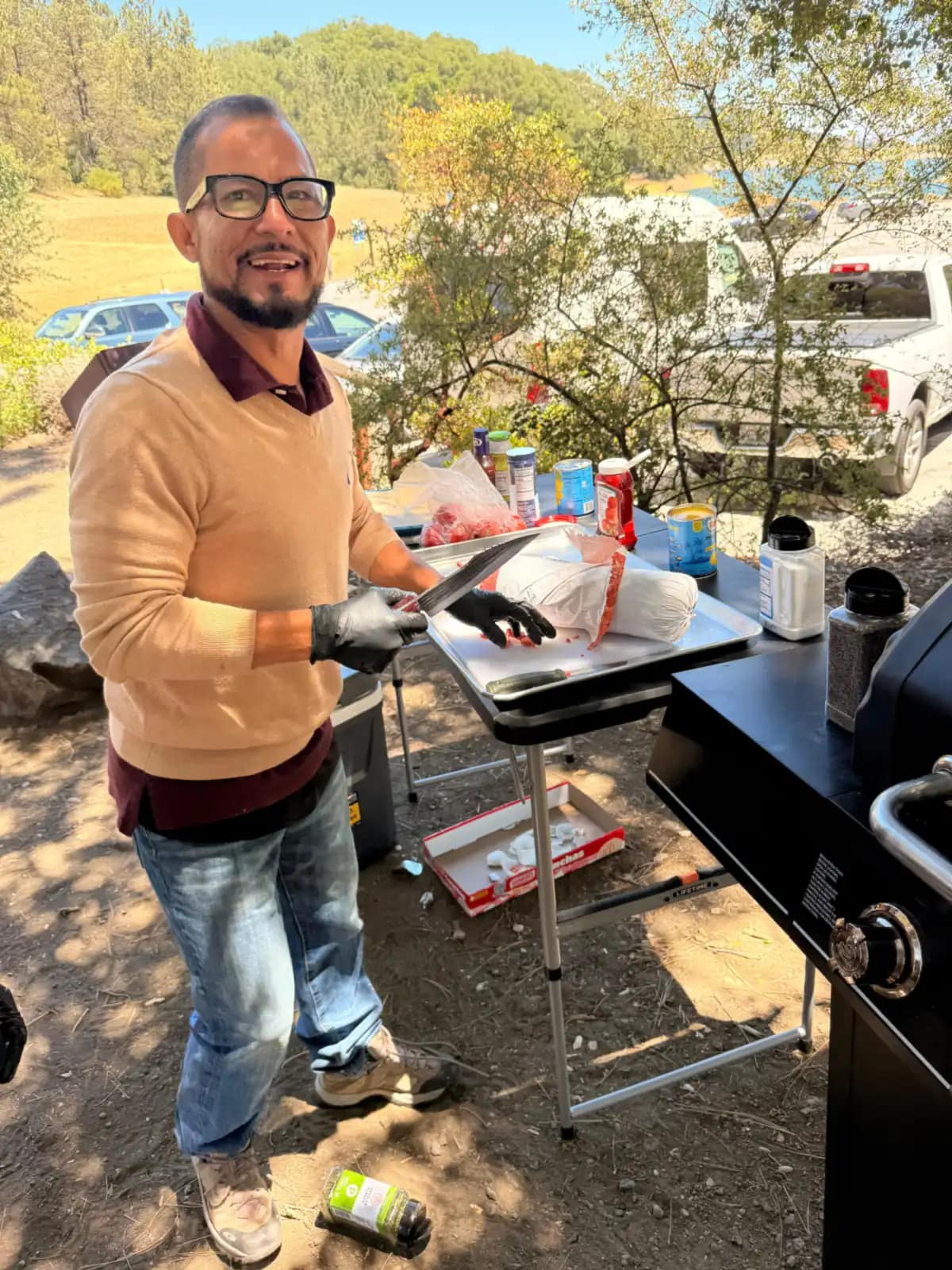 Uno de los hombres corta la carne sobre la bandeja, con guantes y sonriendo a la cámara