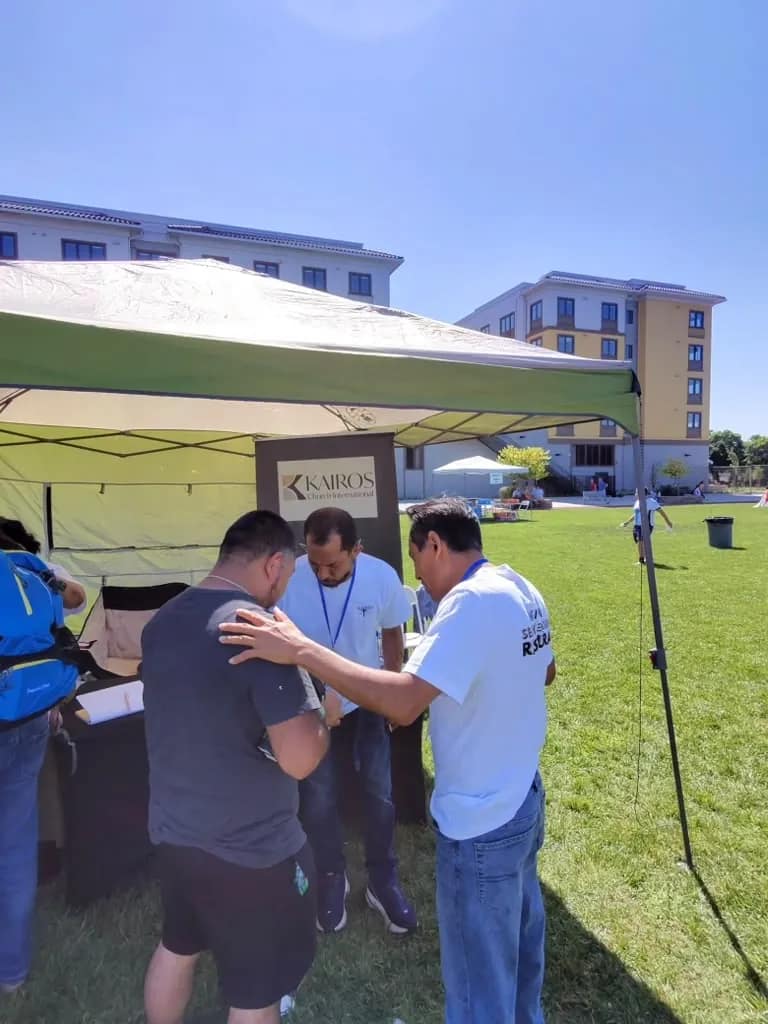 Dos voluntarios oran por un vecino junto al puesto de la iglesia