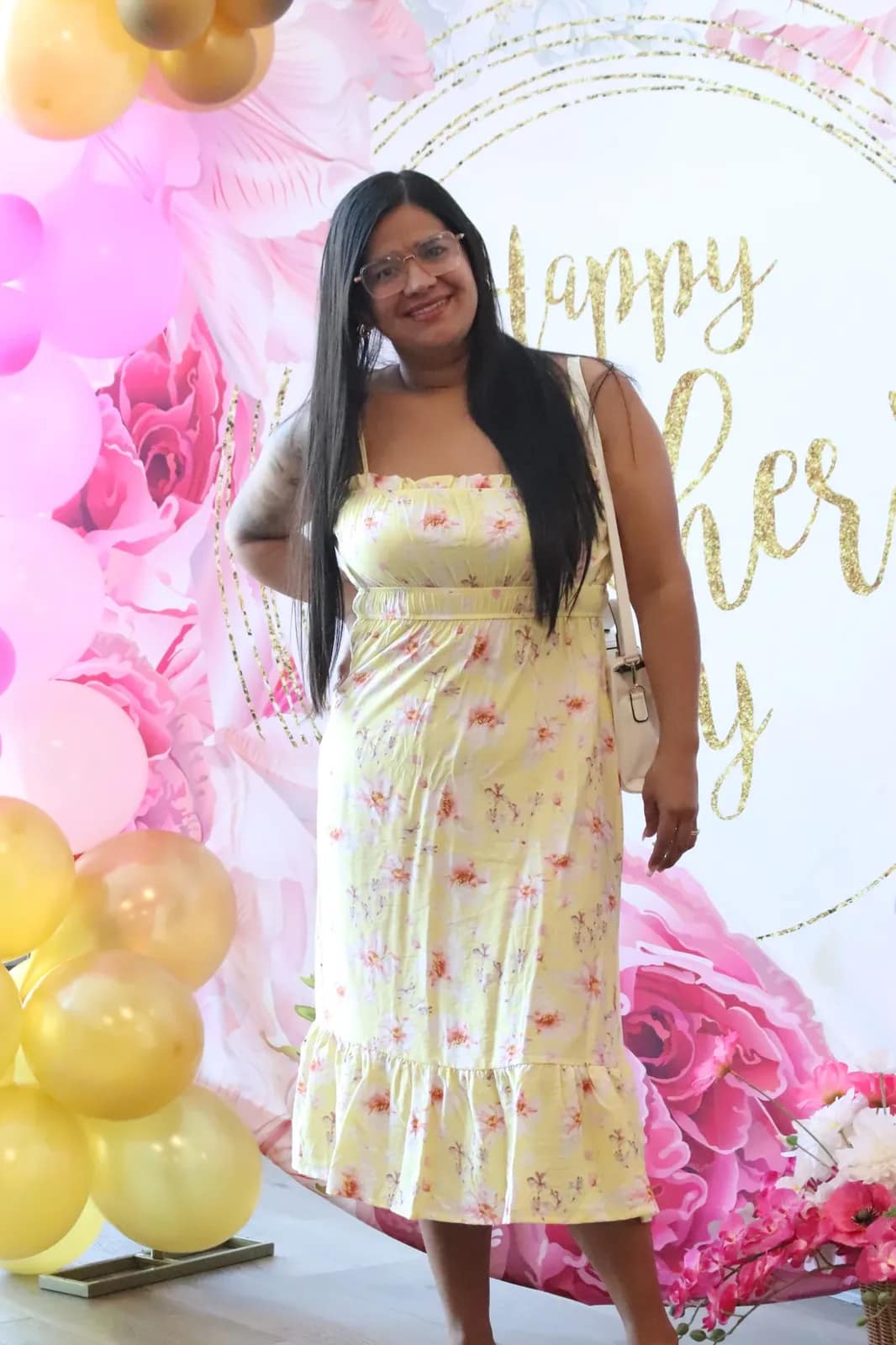 Una joven posa con vestido de flores ante el fondo de la celebración