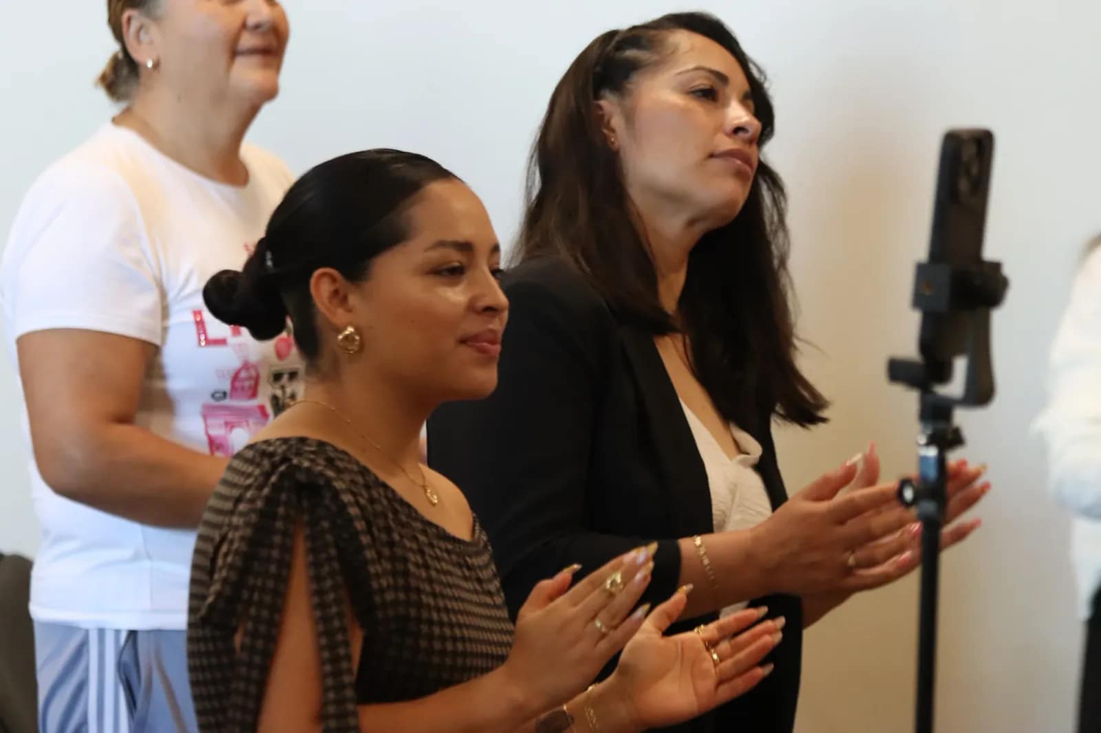 Dos mujeres aplauden de pie durante la alabanza del domingo
