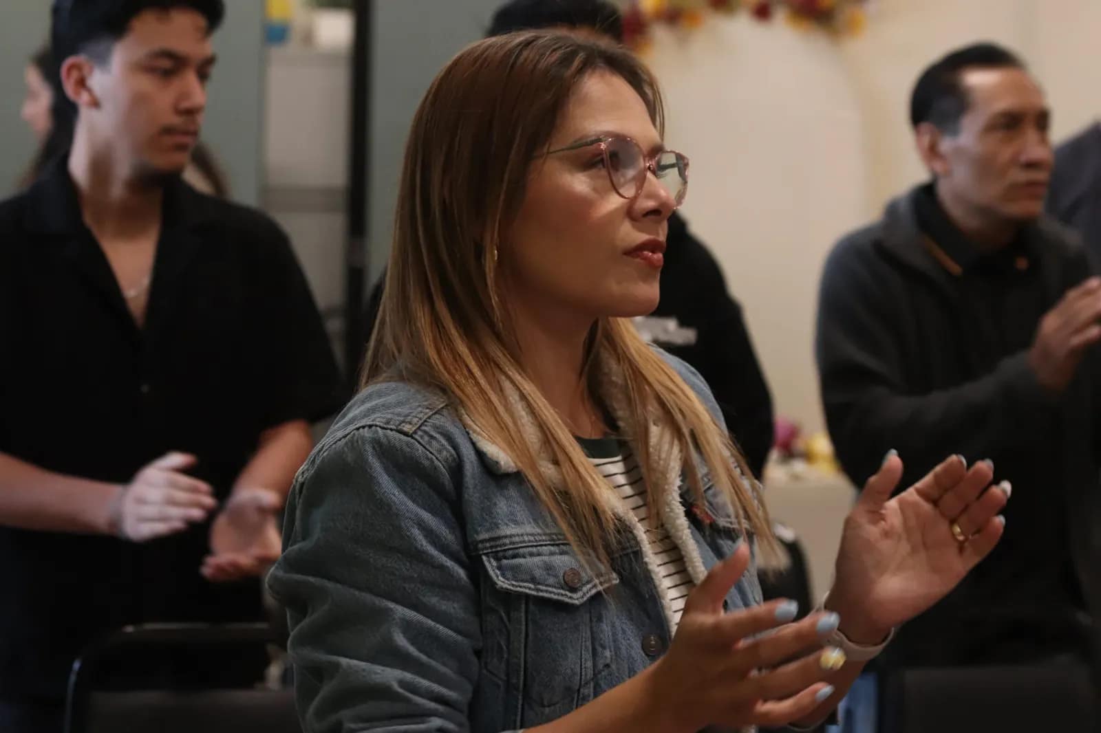 Una mujer aplaude desde su fila durante la alabanza
