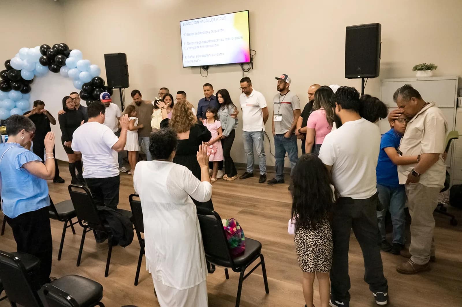 Los niños de la iglesia reciben la bendición al frente, rodeados por los que oran