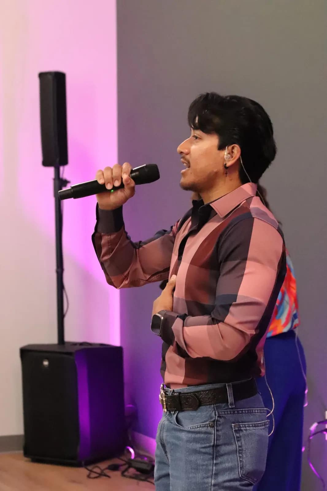Un joven canta al micrófono bajo la luz rosa del escenario