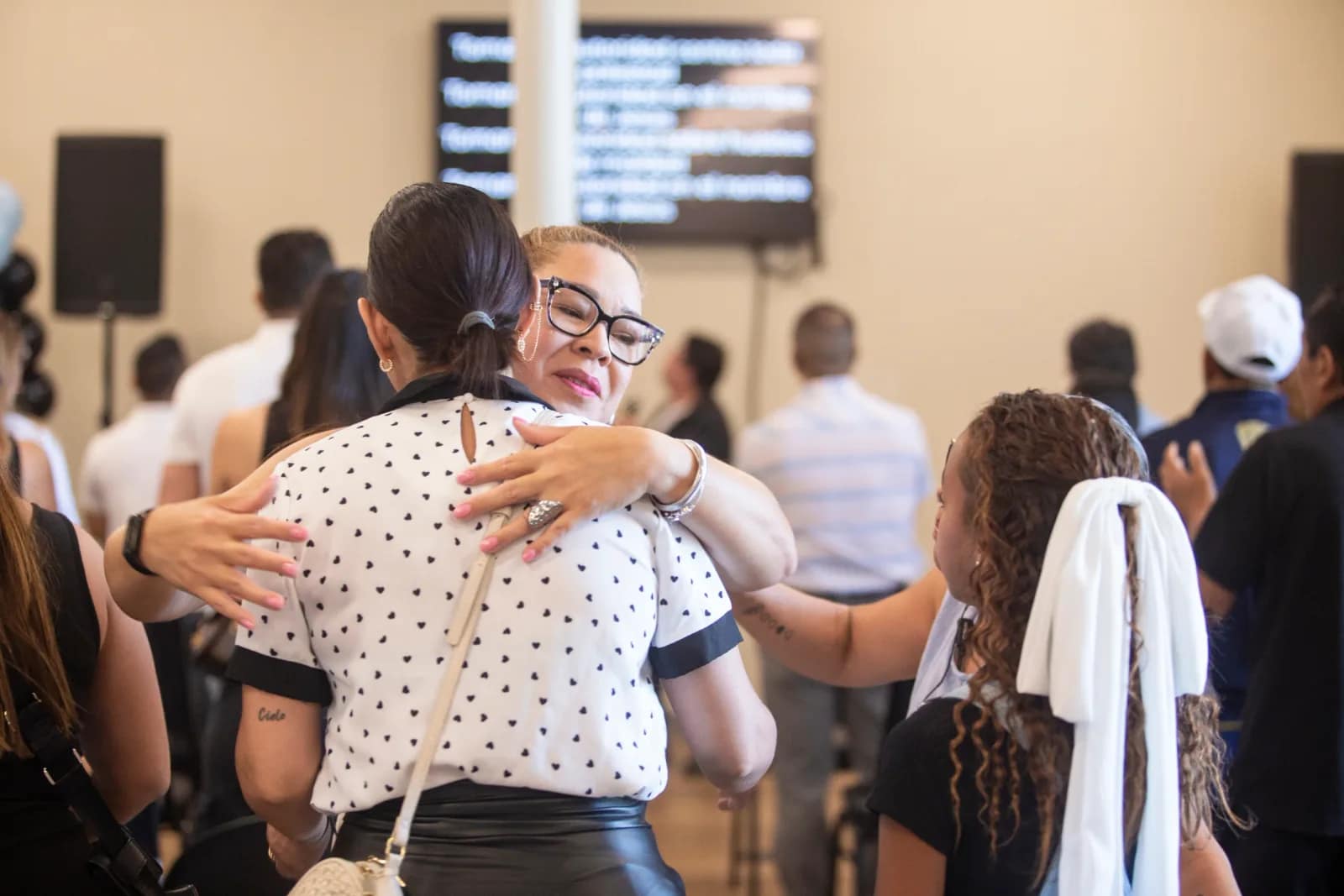 Dos mujeres de la congregación se abrazan en medio del servicio del domingo