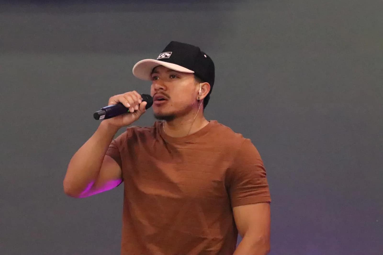 Un joven de gorra canta al micrófono durante la alabanza