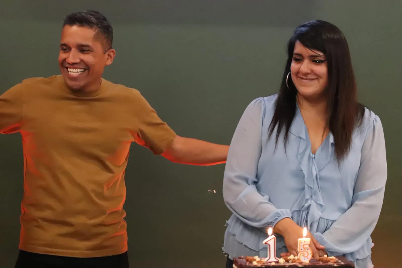 La pareja sonríe ante el pastel con las velas del aniversario