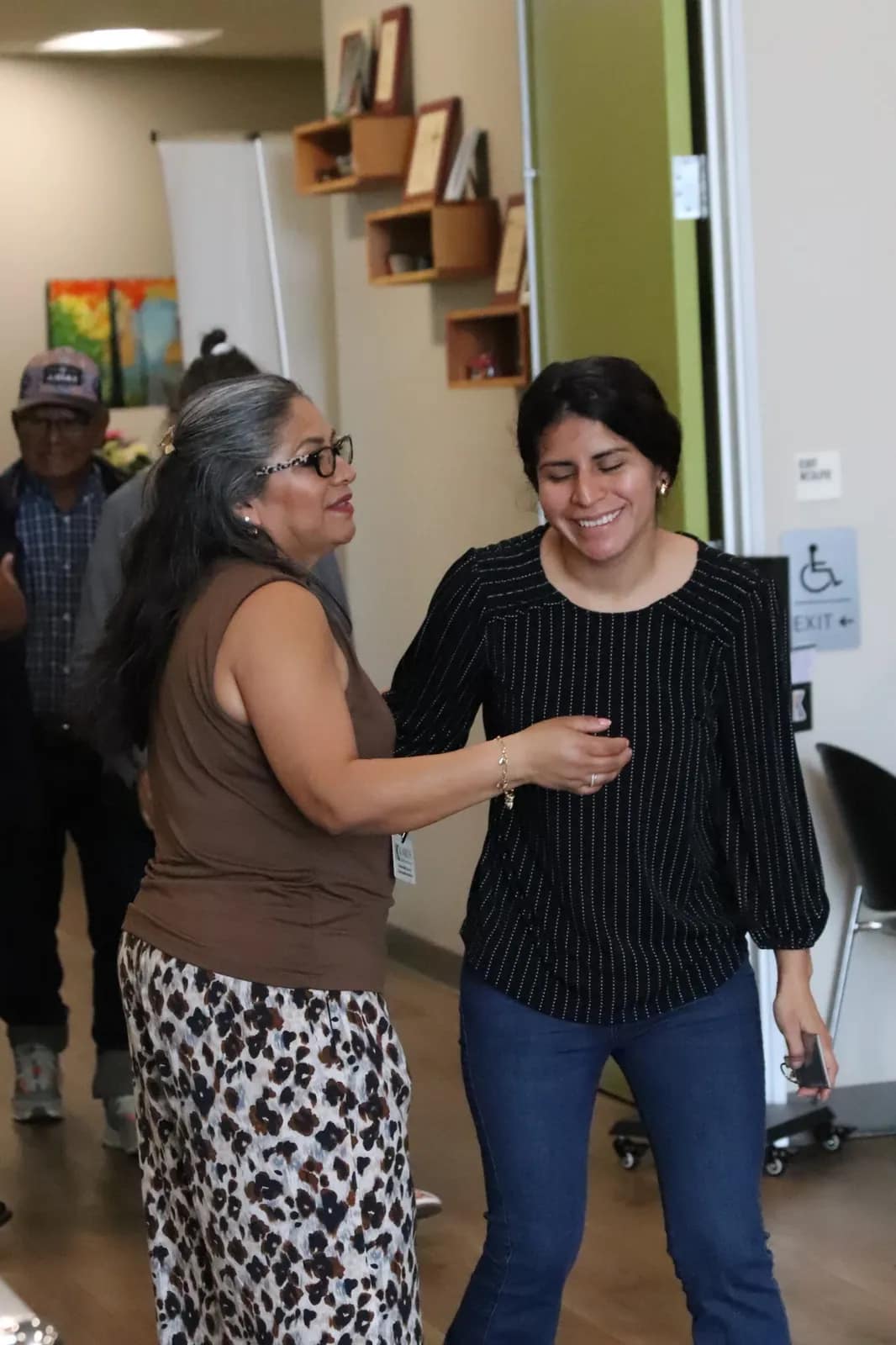 Dos mujeres sonríen durante la entrega de reconocimientos junto a las cajas de regalo