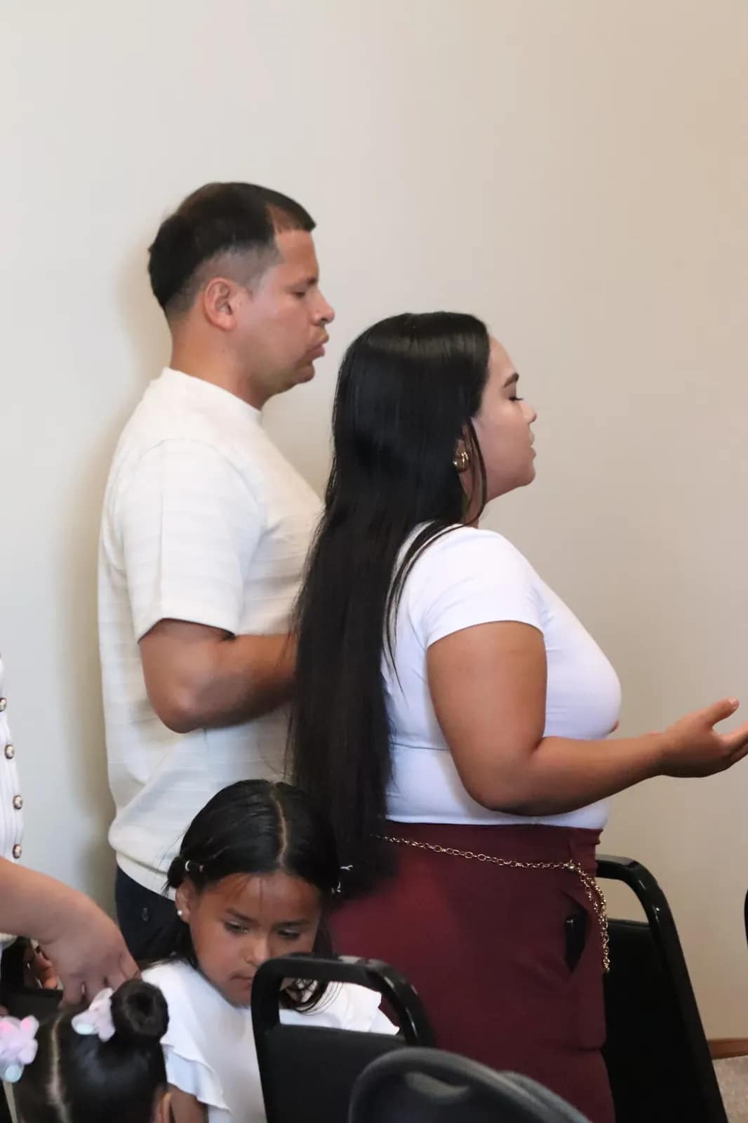 Tres jóvenes se inclinan juntos en oración junto a las sillas