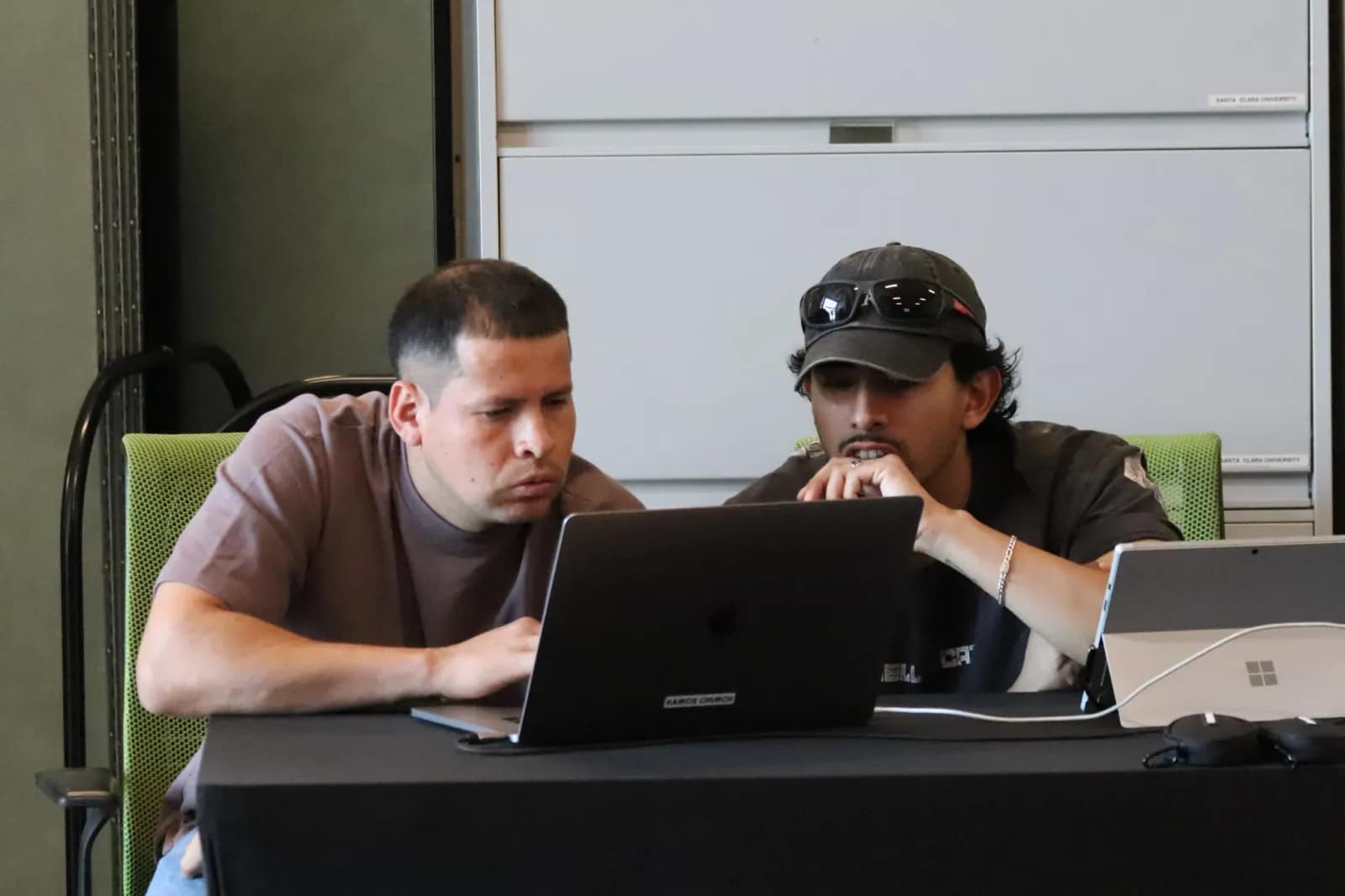 Dos del equipo trabajan en los portátiles de la mesa de producción