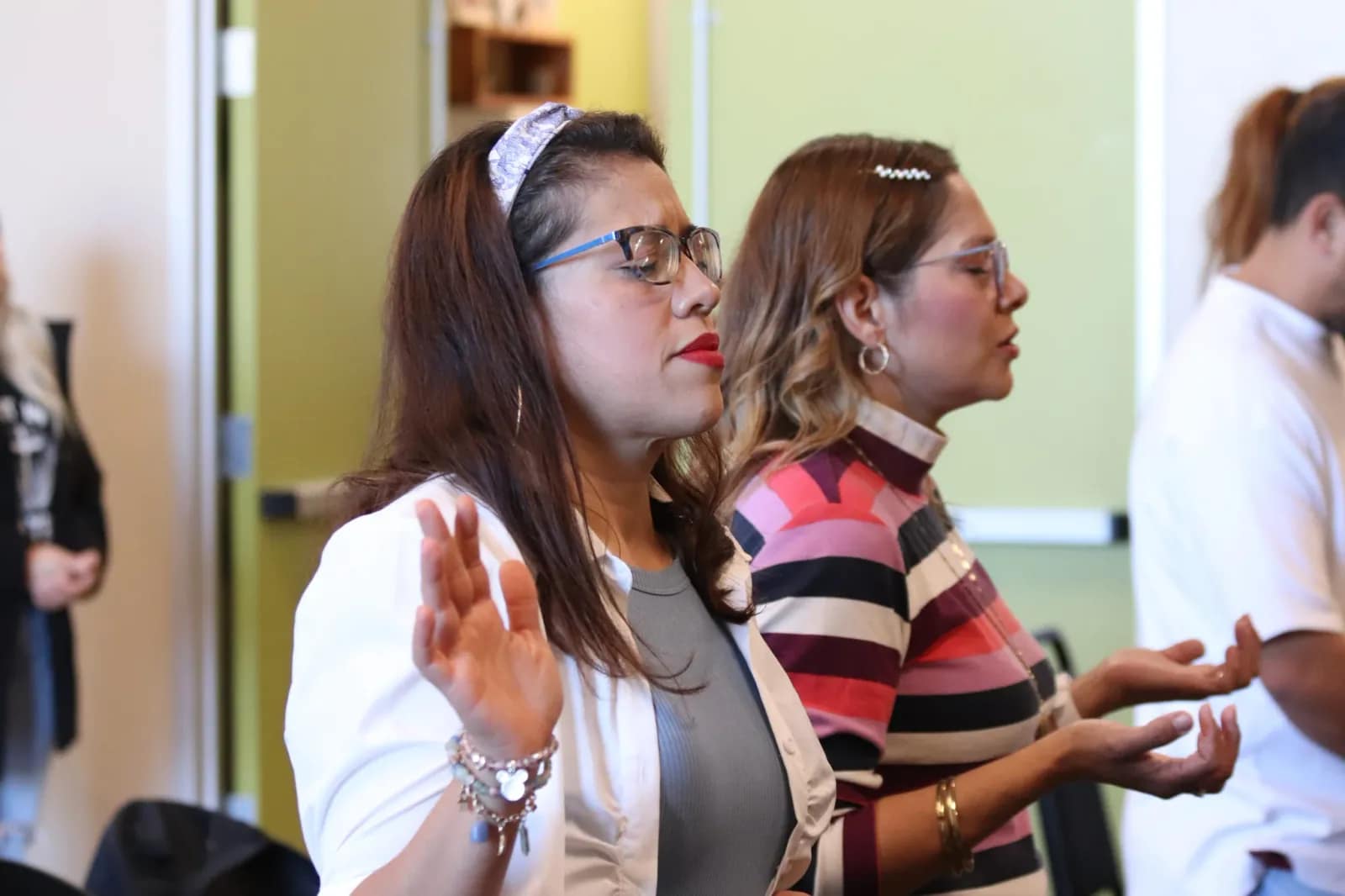 Dos mujeres adoran con las palmas abiertas hacia el frente