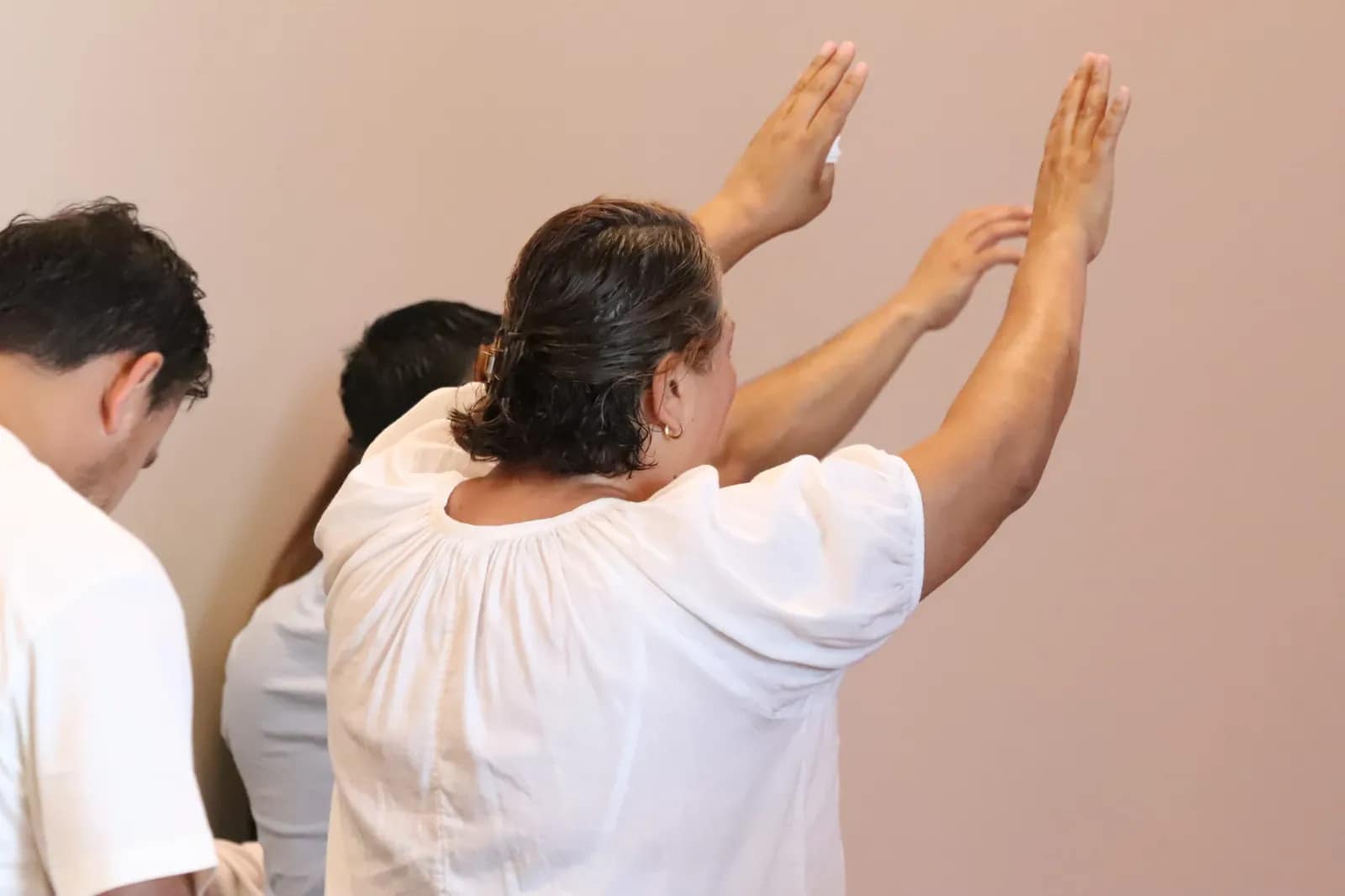 Una mujer levanta las palmas hacia la pared mientras ora