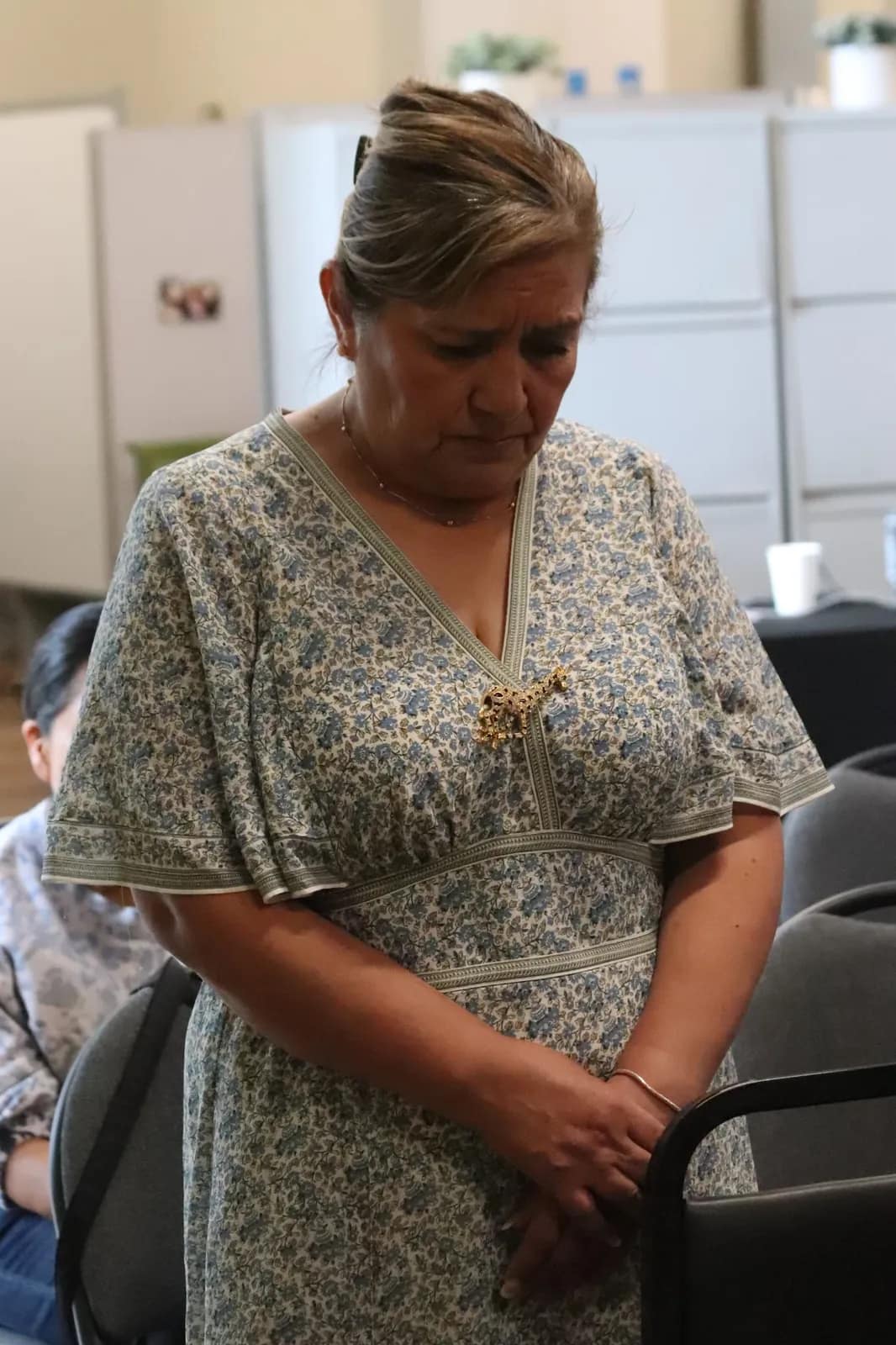 Una señora ora recogida con las manos juntas en su asiento