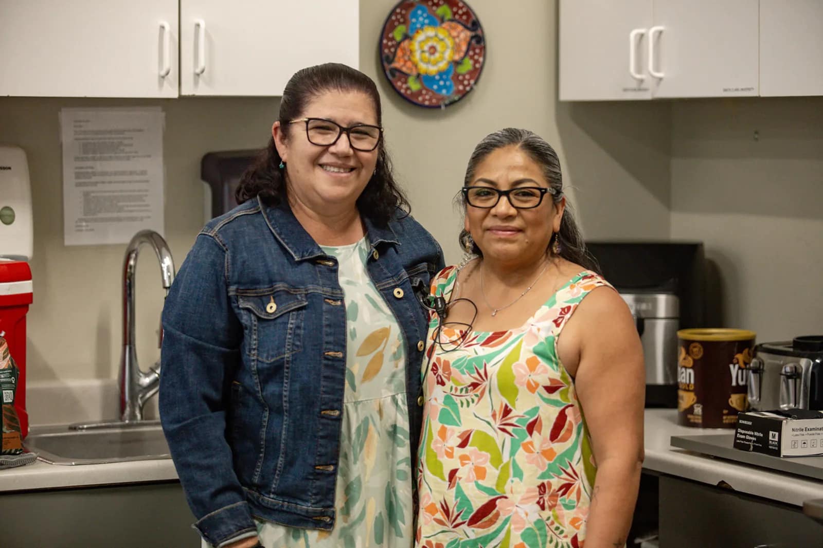 Dos mujeres del equipo de cocina posan sonriendo mientras preparan la comida