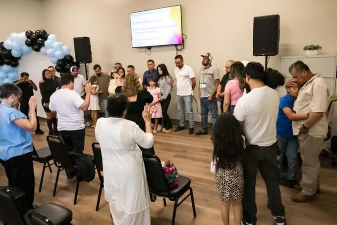 Familias de la congregación orando juntas durante el servicio dominical