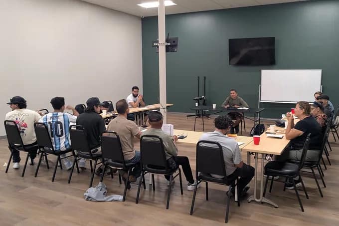 El grupo del estudio bíblico sentado alrededor de las mesas mientras uno de los líderes enseña