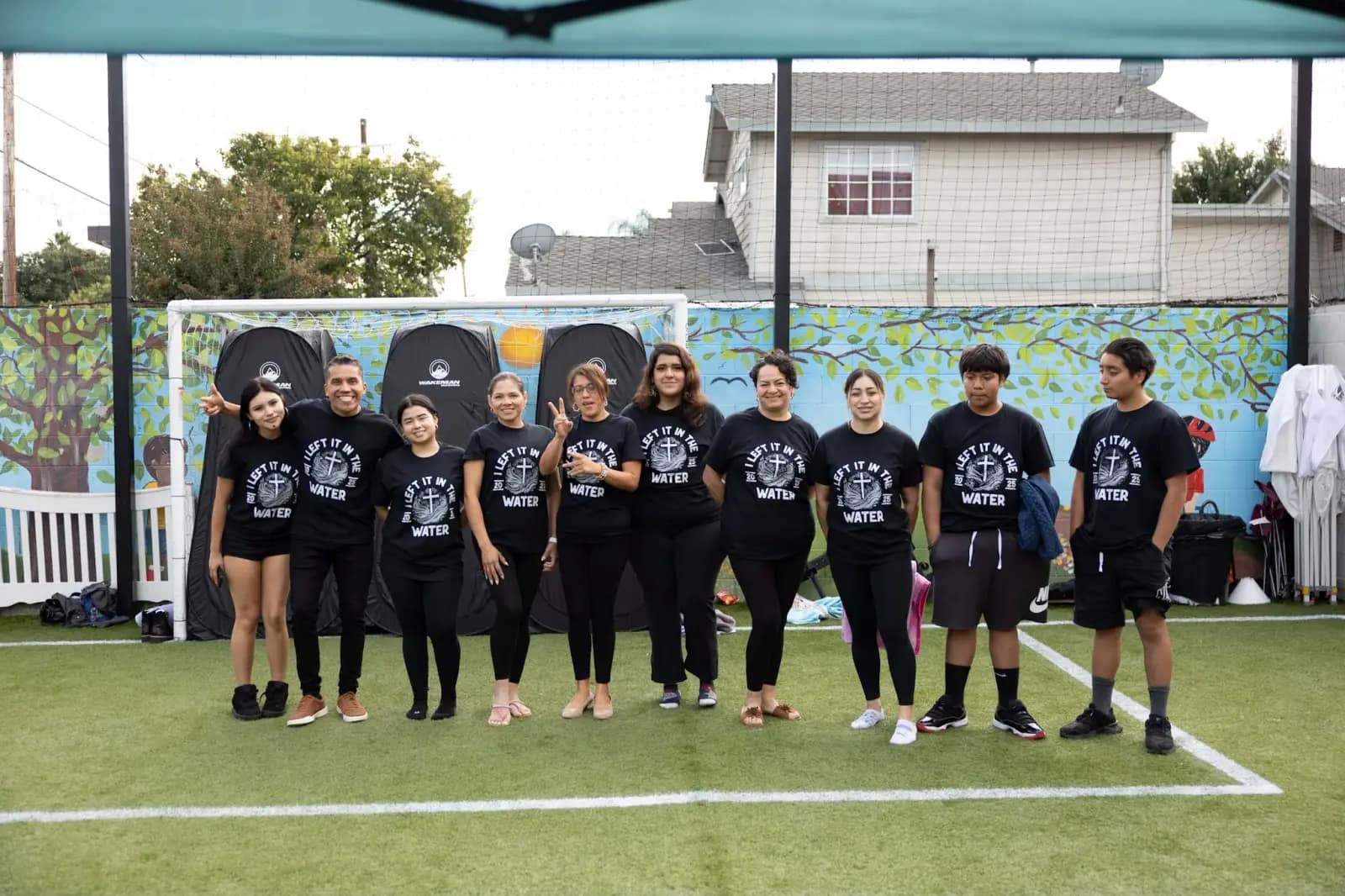 Los bautizados posan en fila sobre el césped con la camiseta «I left it in the water»