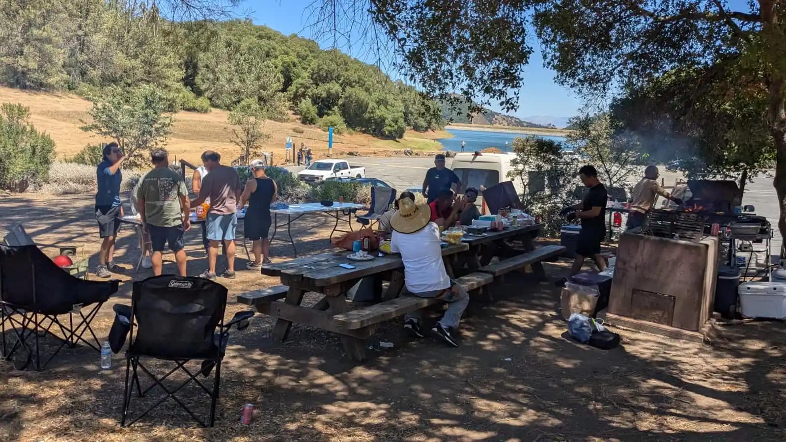El campamento bajo los robles: las sillas, las mesas y el grupo repartido junto al lago
