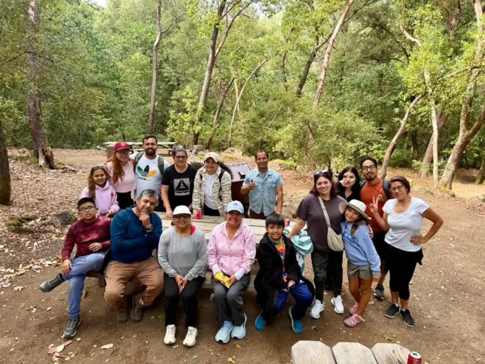 El grupo entero posa alrededor de la mesa de madera al final del sendero, entre los árboles